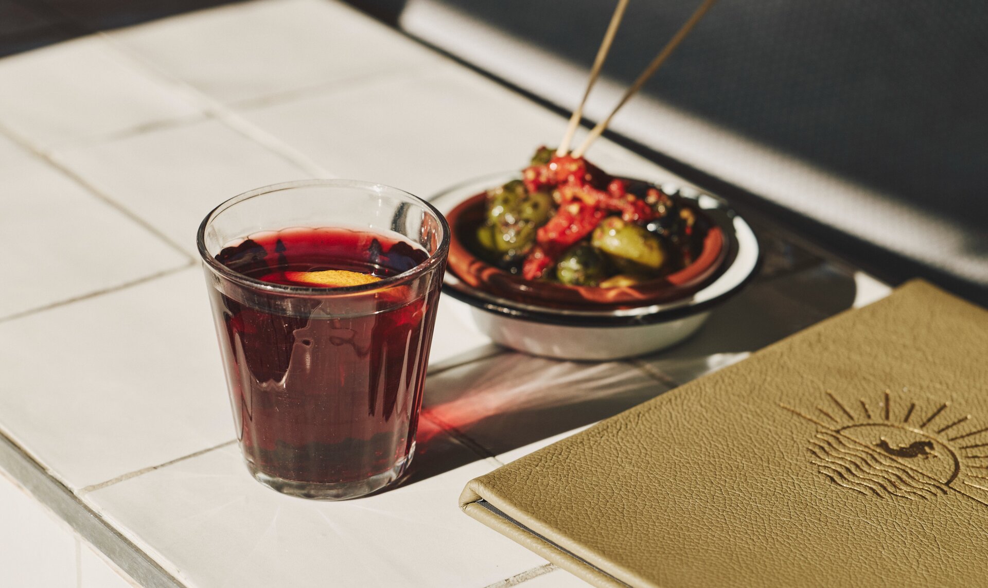 A glass of mulled wine next to a tapas plate and menu.