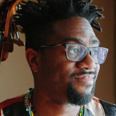 Musician Yunior Terry, wearing spectacles and beard, with guitar neck.