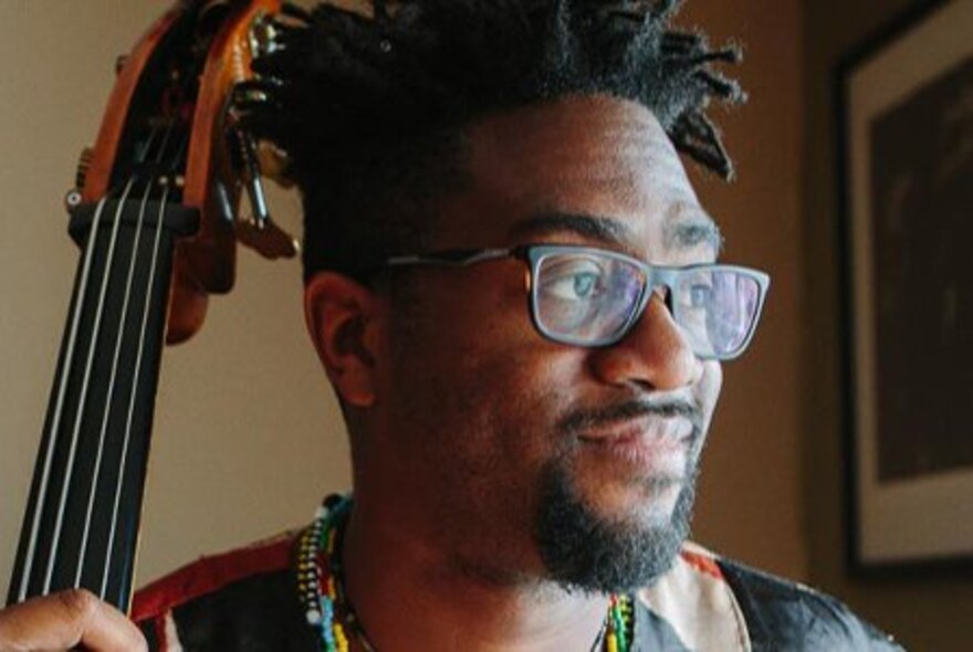 Musician Yunior Terry, wearing spectacles and beard, with guitar neck.