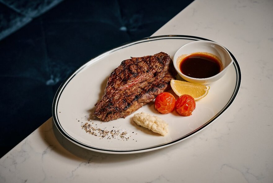 Platter of food with garnishes and sauce on a white table.