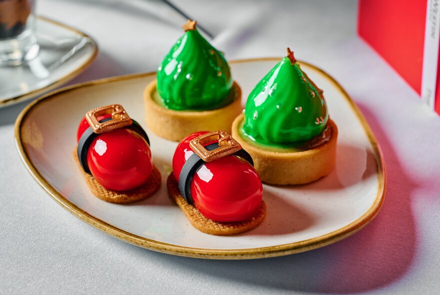 A plate of festive-themed high tea sweet items, with red and green glazing.