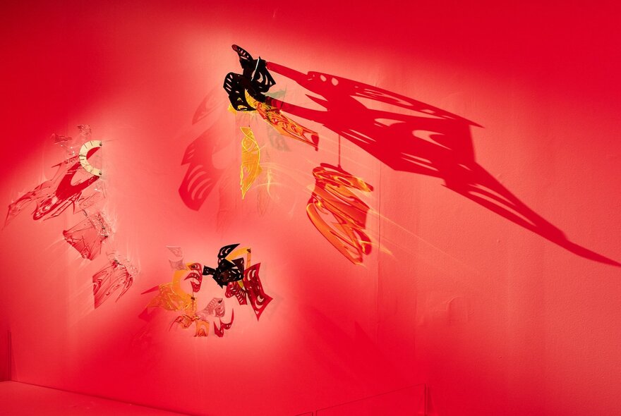 Mobile art pieces in a  gallery space with red walls