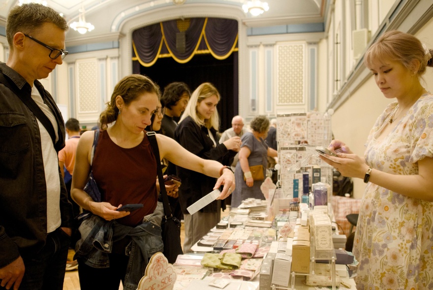 People wandering the stalls at the Melbourne Pen and Stationery Show, looking at products on display.