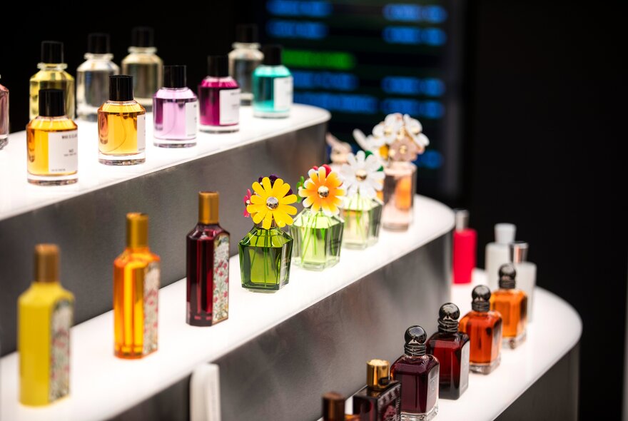 A multi-tier display stand filled with various glass perfume bottles inside a store.