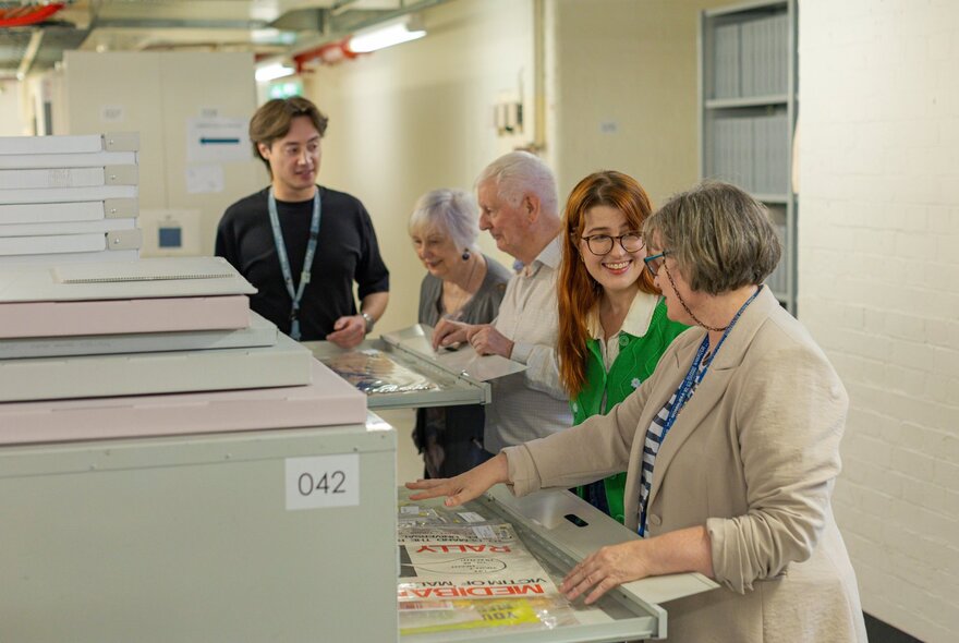 A group of people looking at museum artefacts in the archives of the State Library of Victoria.