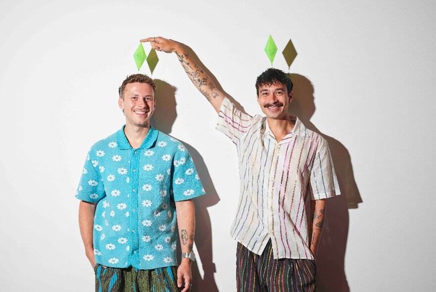 Design duo Josh & Matt Design wearing summery short-sleeved shirts in blue and stripes, with triangles on their heads.