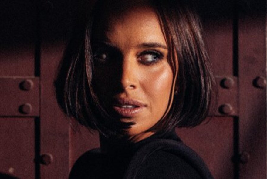 Singer with short dark hair, looking sharply to her left.