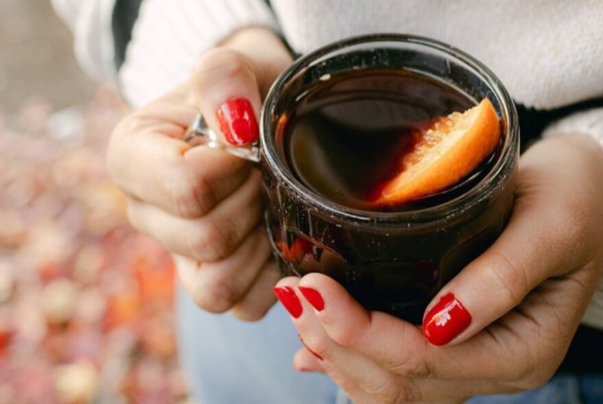 A glass mug of mulled wine with an orange wedge.