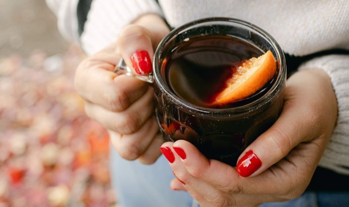 A glass mug of mulled wine with an orange wedge.