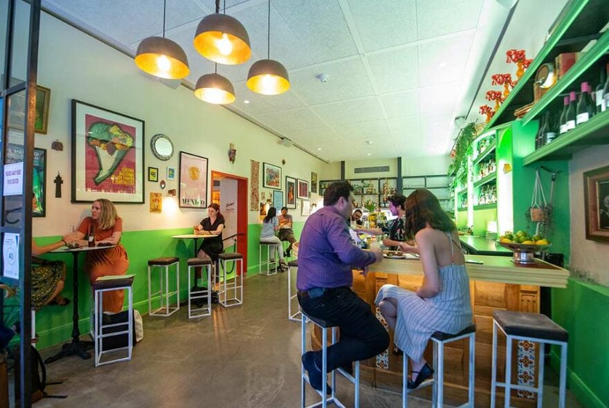 People sitting at the bar in a bright green restaurant.