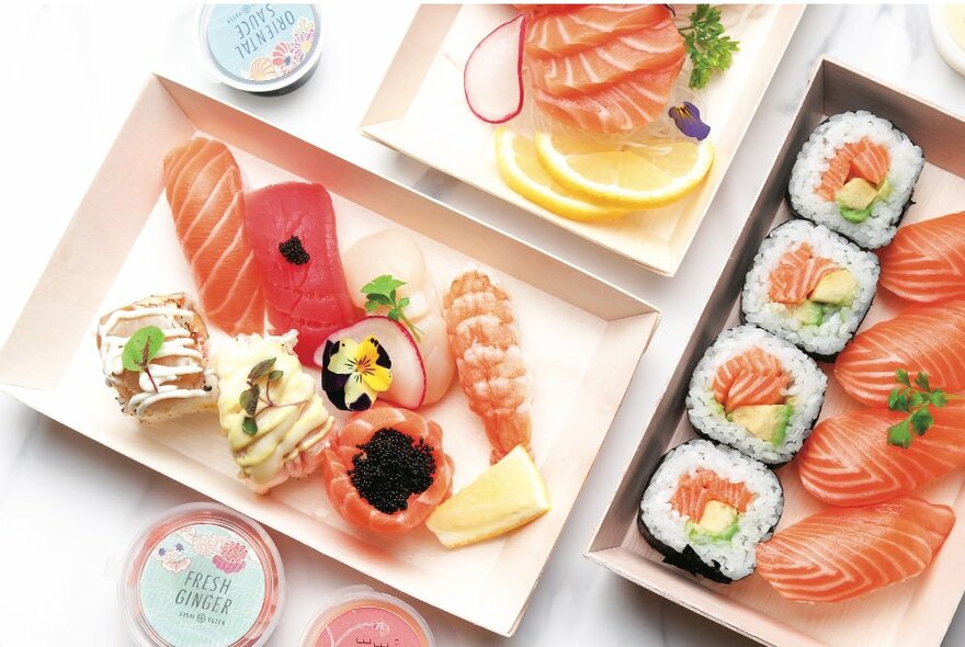 Several trays of sushi featuring salmon and sushi.