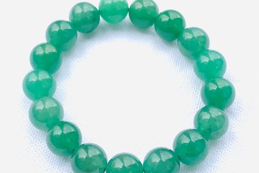 A bracelet made from a string of jade beads, displayed on a white background.