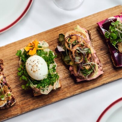 four open sanwiches with betroot and sprouts, pickles and onions, parsley and boiled eggs on a wooden serving board