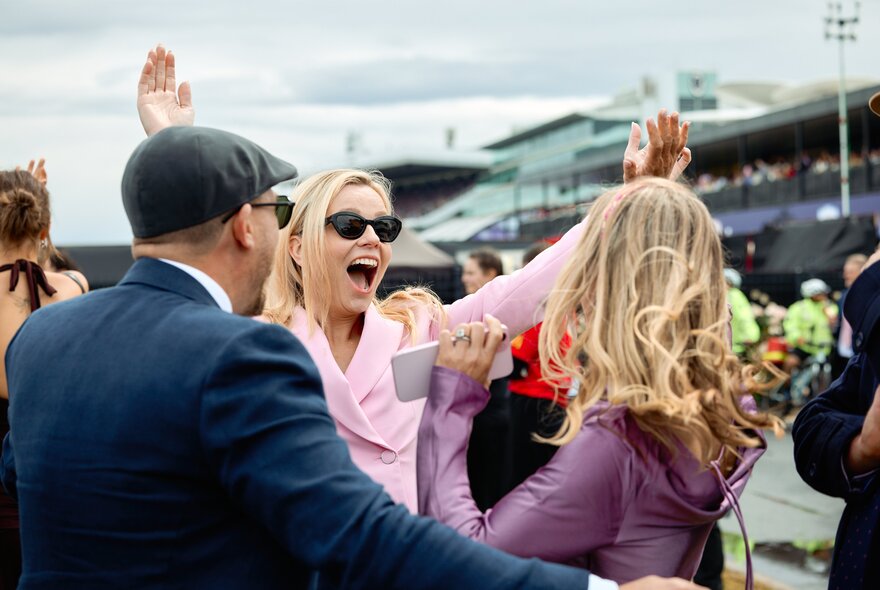 People celebrating with raised arms and screams at the races.
