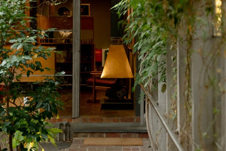 Looking at a pathway with foliage leading up to a house with warm tones. 