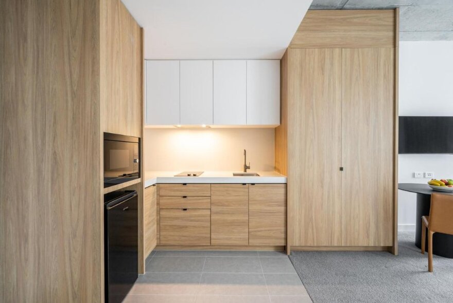The wood panelled open plan kitchen in a suite at the Nesuto Docklands Apartment Hotel. 
