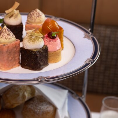 A high tea experience featuring a tiered stand filled with pastries and savoury bites.