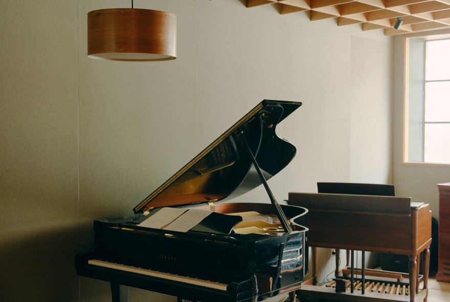 A grand piano situated in a room, paired with another keyboard instrument behind it.