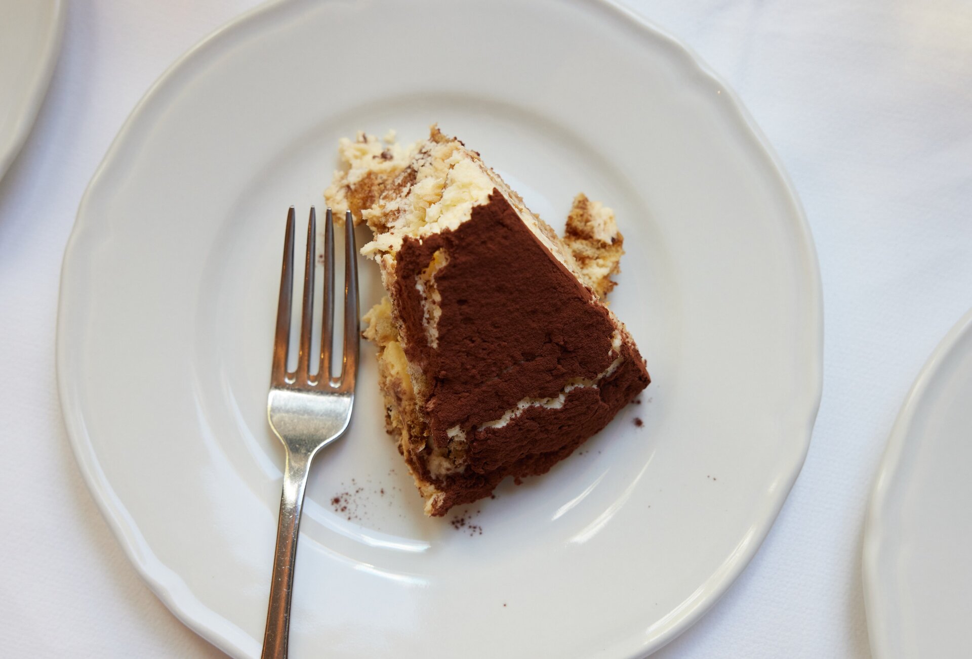 A slice of tiramisu on a white plate with a silver fork.