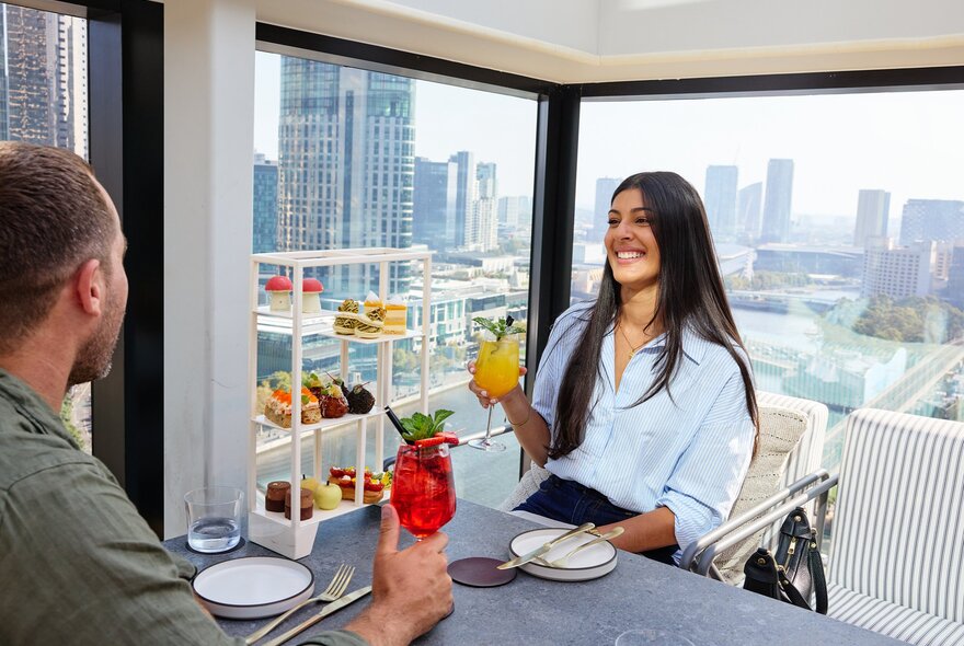 Man and woman drinking cocktails with city views