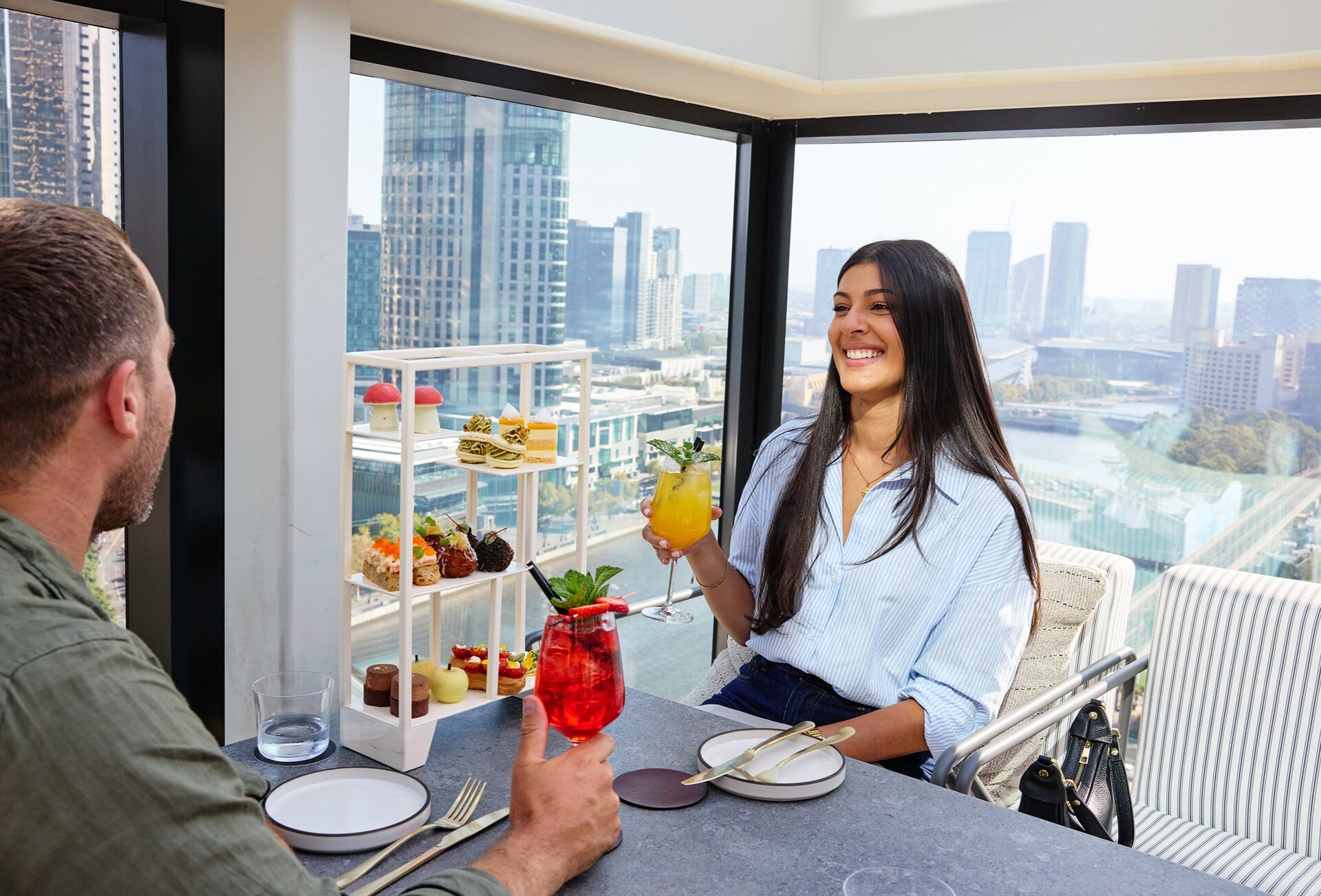 Man and woman drinking cocktails with city views
