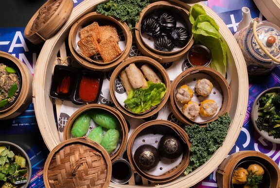A bamboo steamer basket filled with Yum Cha dishes, including spring rolls and dumplings.