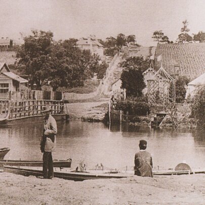 Historic photo of people on the banks of the Yarra with boats, at the location where Punt Road crosses the river today.
