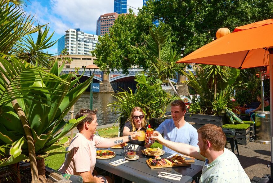 A group of friends are cheersing at an outdoor restaurant