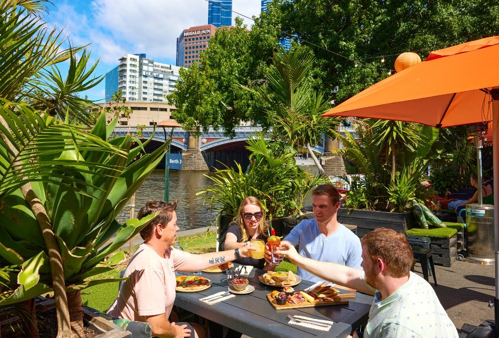 A group of friends are cheersing at an outdoor restaurant