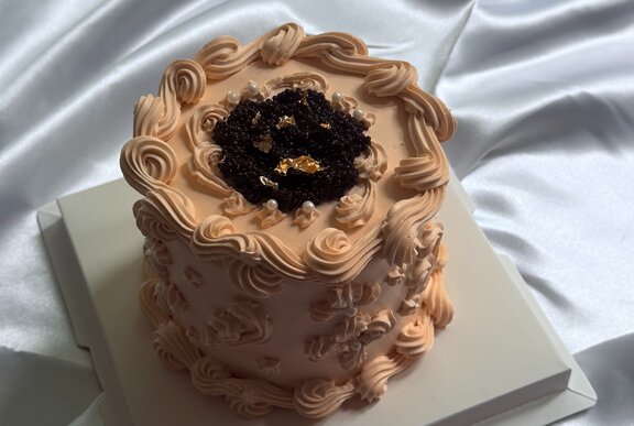 A decorated cake with a unique, braided or coiled frosting design around the sides.