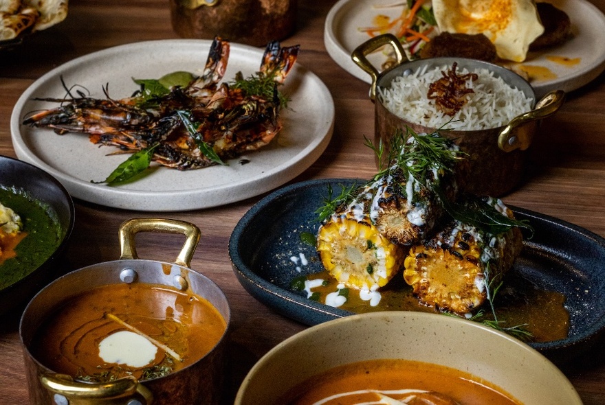 A table loaded with dishes of food including rice, meat, curry and vegetables.