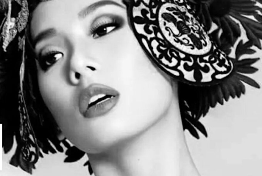 Model wearing elaborate head ornament, looking to the side.