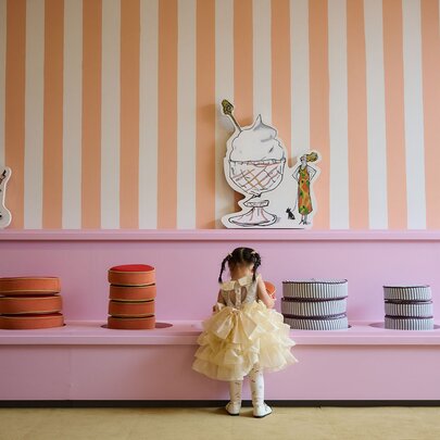 A little girl looking at a colourful display of cushions in an art gallery.