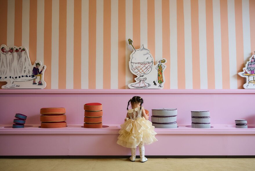 A little girl looking at a colourful display of cushions in an art gallery.