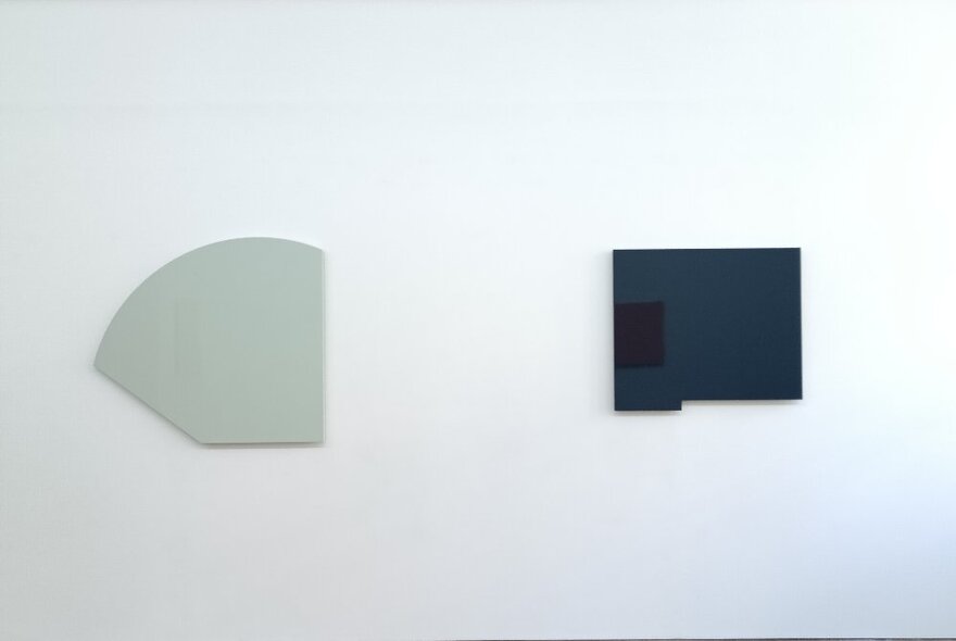 Two large, flat and solid coloured artworks hanging on a white gallery wall.