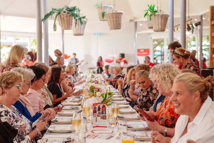 A very long table with women enjoying afternoon tea, 