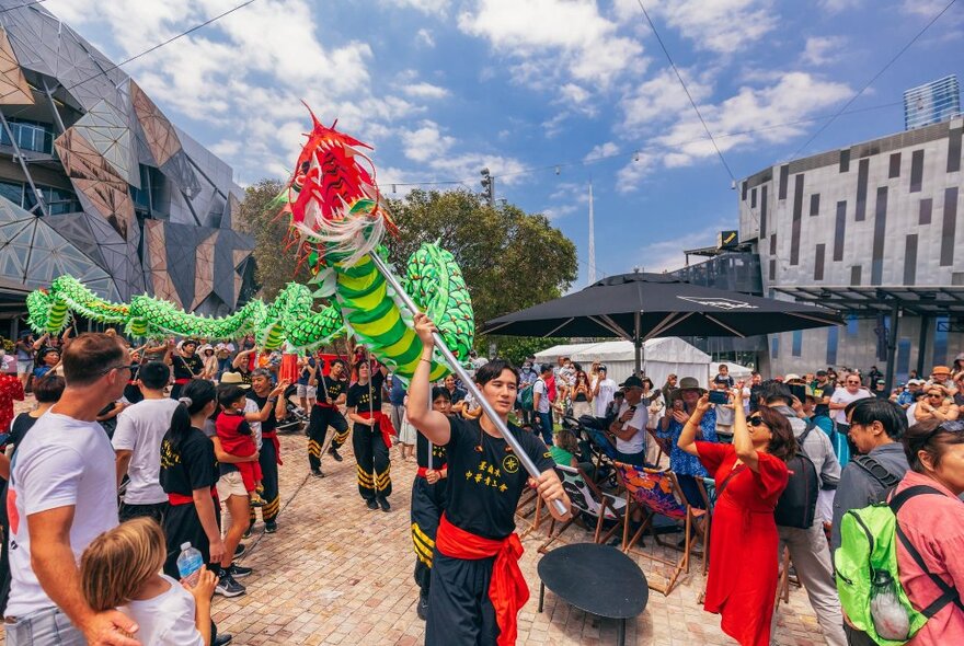 Dragon dancers at Fed Square, with crowds of people watching on.