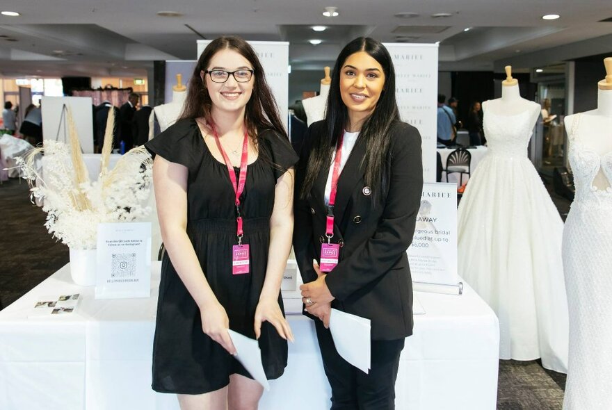 Wedding stylists wearing black outfits standing in front of white table settings and gowns.