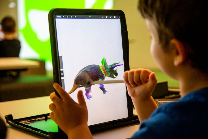 A child playing with an ipad showing a dinosaur. 