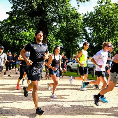 A large group of people in active wear all running on a path in park. 
