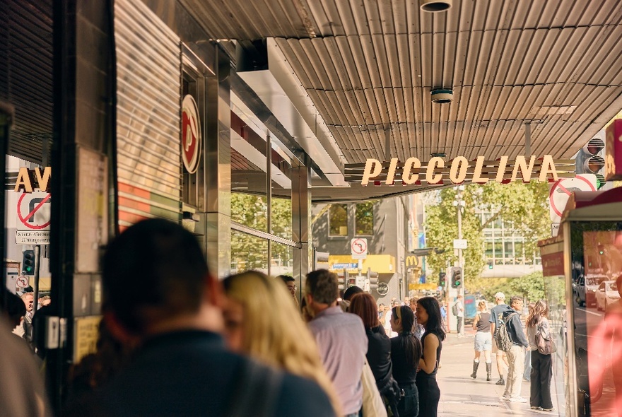 People lined up in a queue waiting to enter a Piccolina gelato shop in a Melbourne city street.