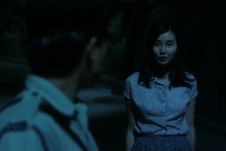 A still from the movie, Days of Being Wild, showing a young woman talking to a police officer in the foreground.