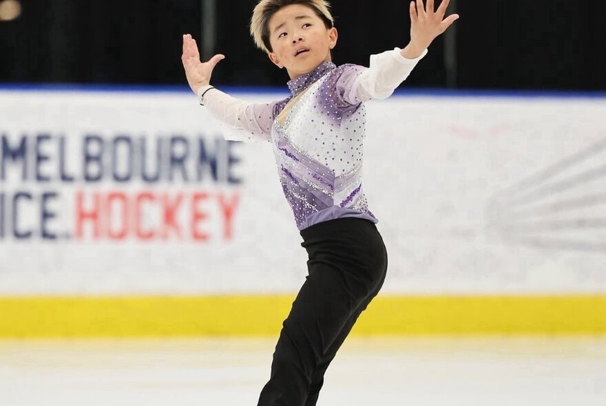 A figure skater performing on ice with arms outstretched. 