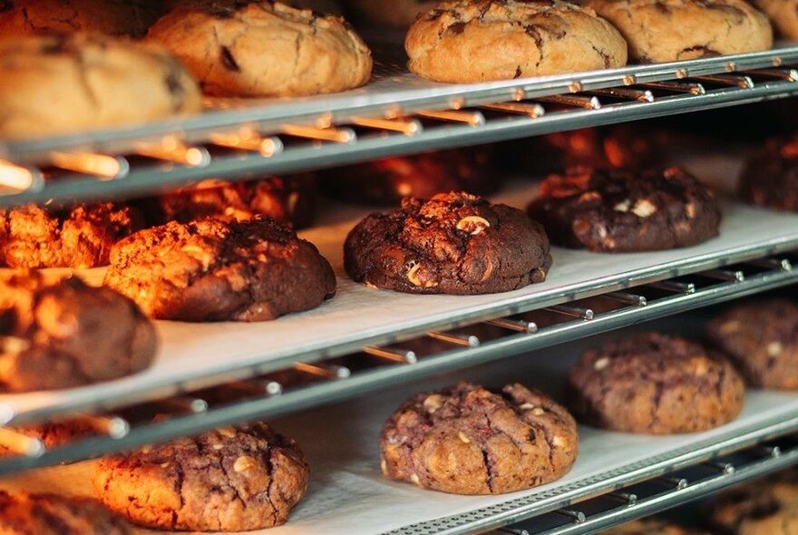 Shelves of freshly baked cookies on trays in a shop.