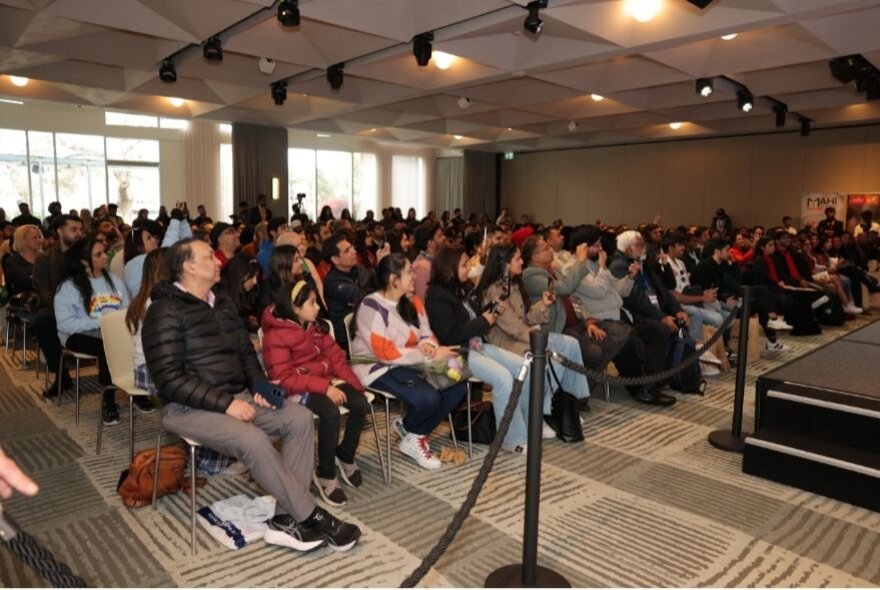 An audience of people seated listening to a speaker. 