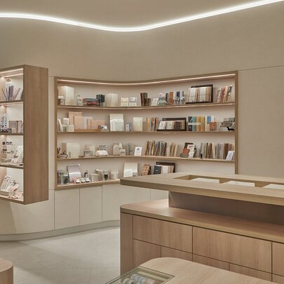 Store interior with beige walls and wooden display cases and shelves, displaying stationery goods.