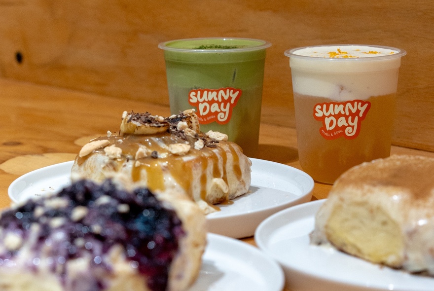 Branded coffee and matcha drinks with iced scrolls on plastic plates.