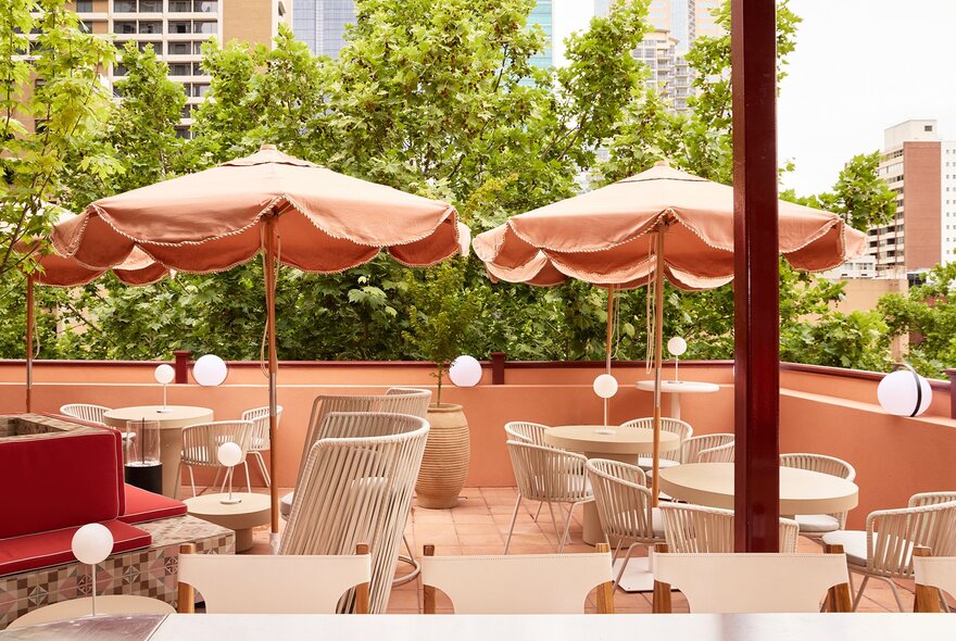 A pink rooftop bar with umbrellas and trees.