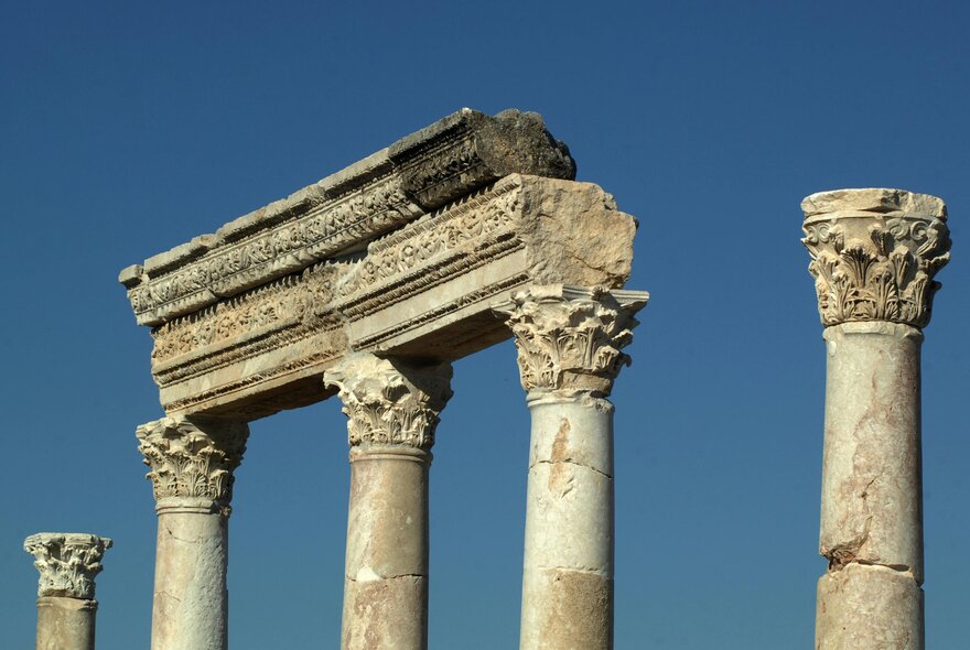 A portion of an ancient Roman colonnade at an archaeological site, against a blue sky.
