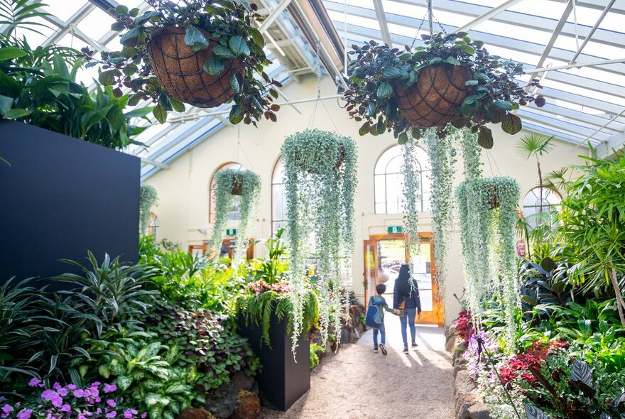 A mother and child are walking through a garden conservatory